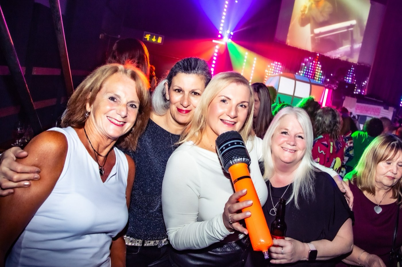 Four friends posing with an orange inflatable microphone