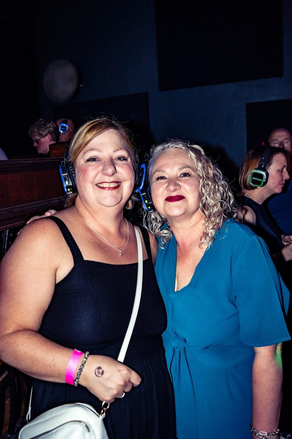 Two friends smiling in light-up headphones